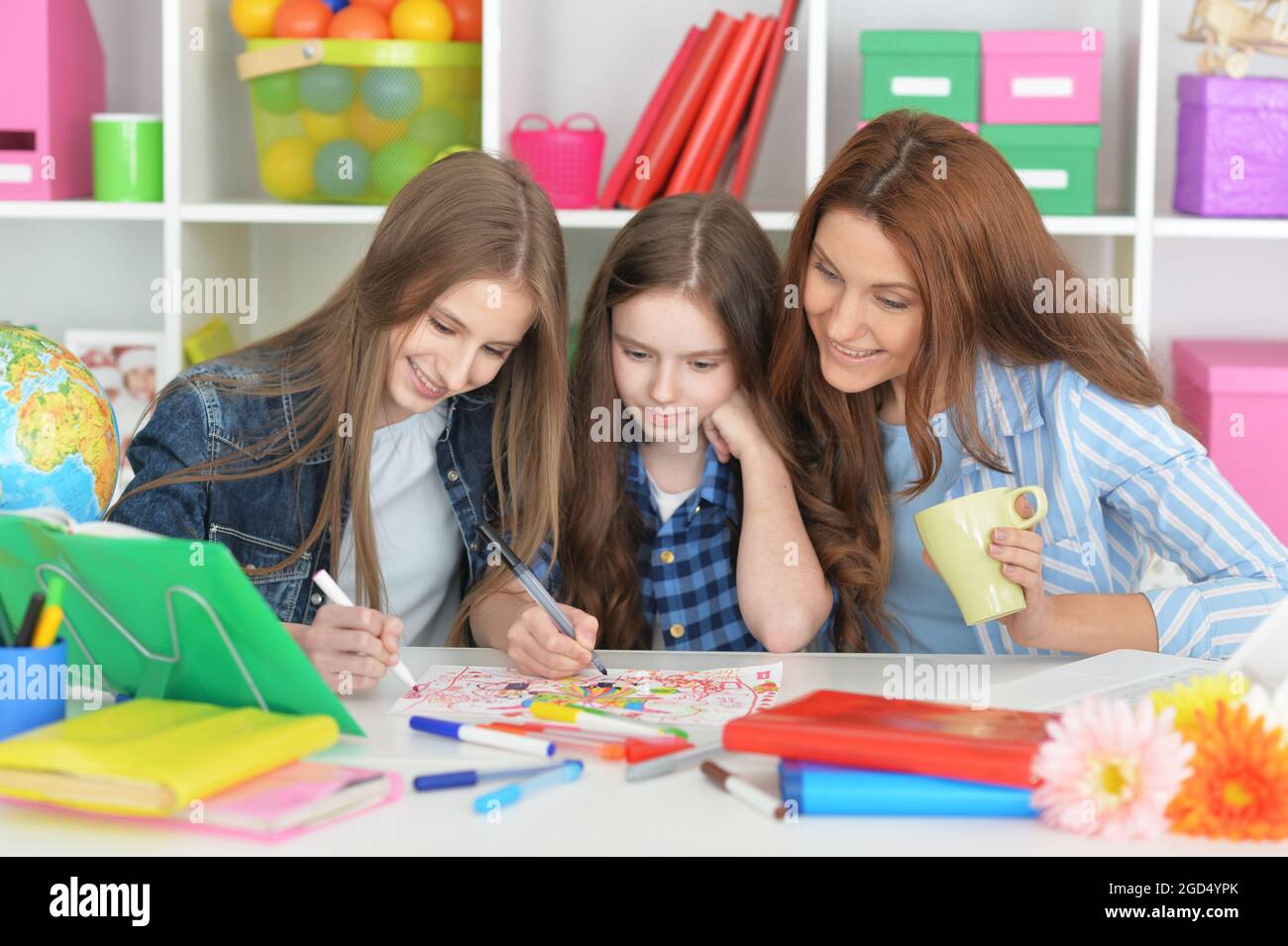 Teacher with two girls drawing together at art class Stock Photo - Alamy
