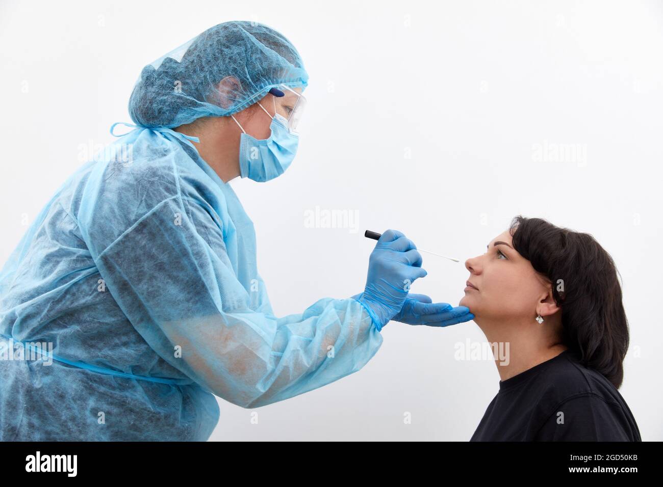 Doctor in a protective suit taking a throat and nasal swab from a patient to test for possible coronavirus or covid infection Stock Photo