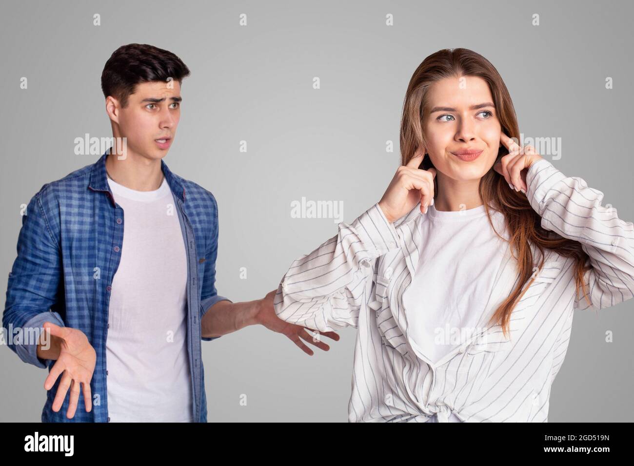 Quarrel and showdown. Sad woman covers her ears with fingers, upset man expresses negative emotions, gestures, gives arguments and looks at lady, isol Stock Photo