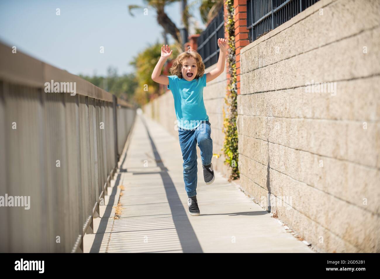 Excited energetic boy child scream running on summer promenade, excitement Stock Photo