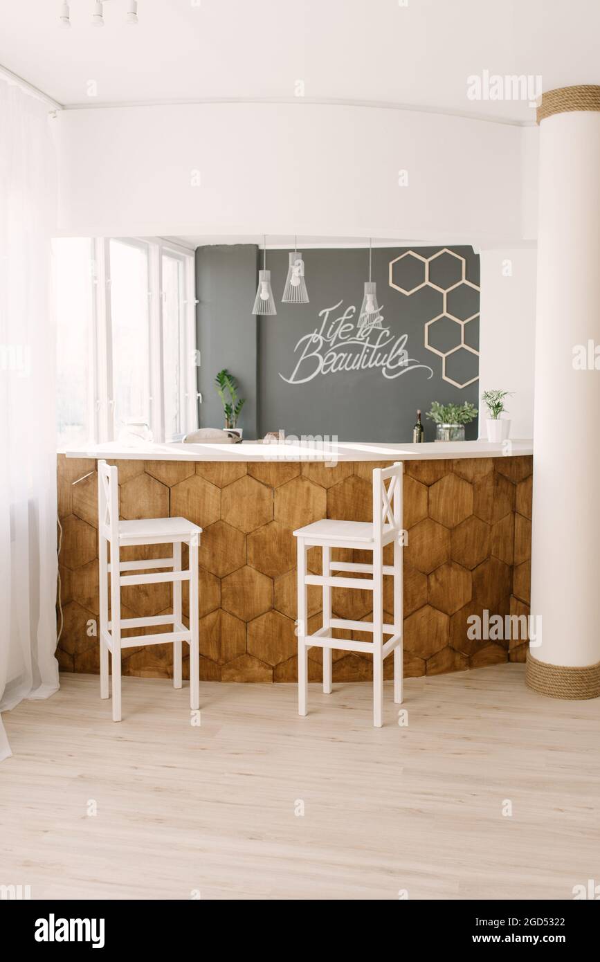 A stylish modern bar counter decorated with wooden tiles and two white bar  stools in the living room of the house. Scandinavian interior design Stock  Photo - Alamy