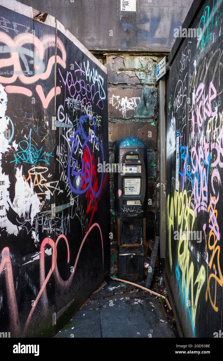 A neglected parking meter in Liverpool city centre surrounded by graffiti and litter. Stock Photo