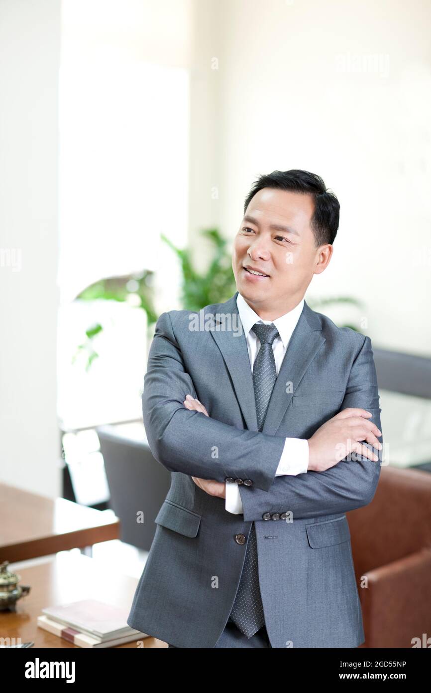 Mature businessman in office with arms crossed Stock Photo - Alamy