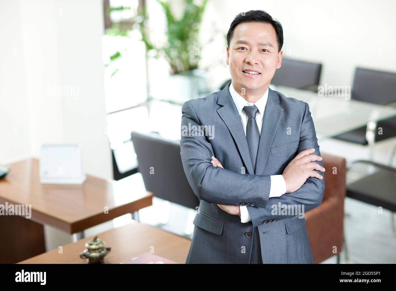 Mature businessman in office with arms crossed Stock Photo - Alamy