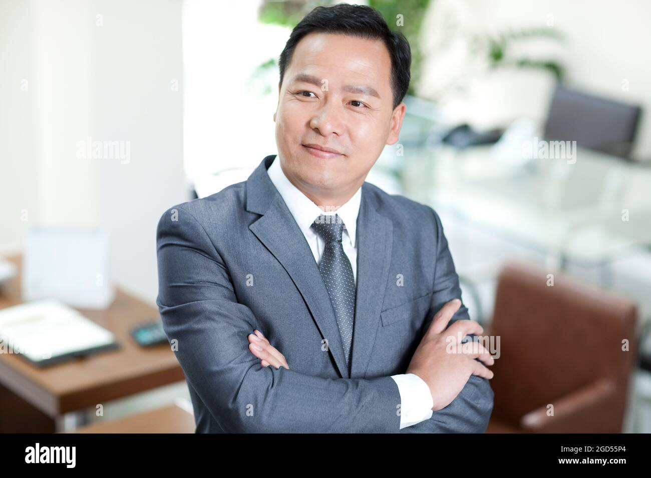 Mature businessman in office with arms crossed Stock Photo - Alamy