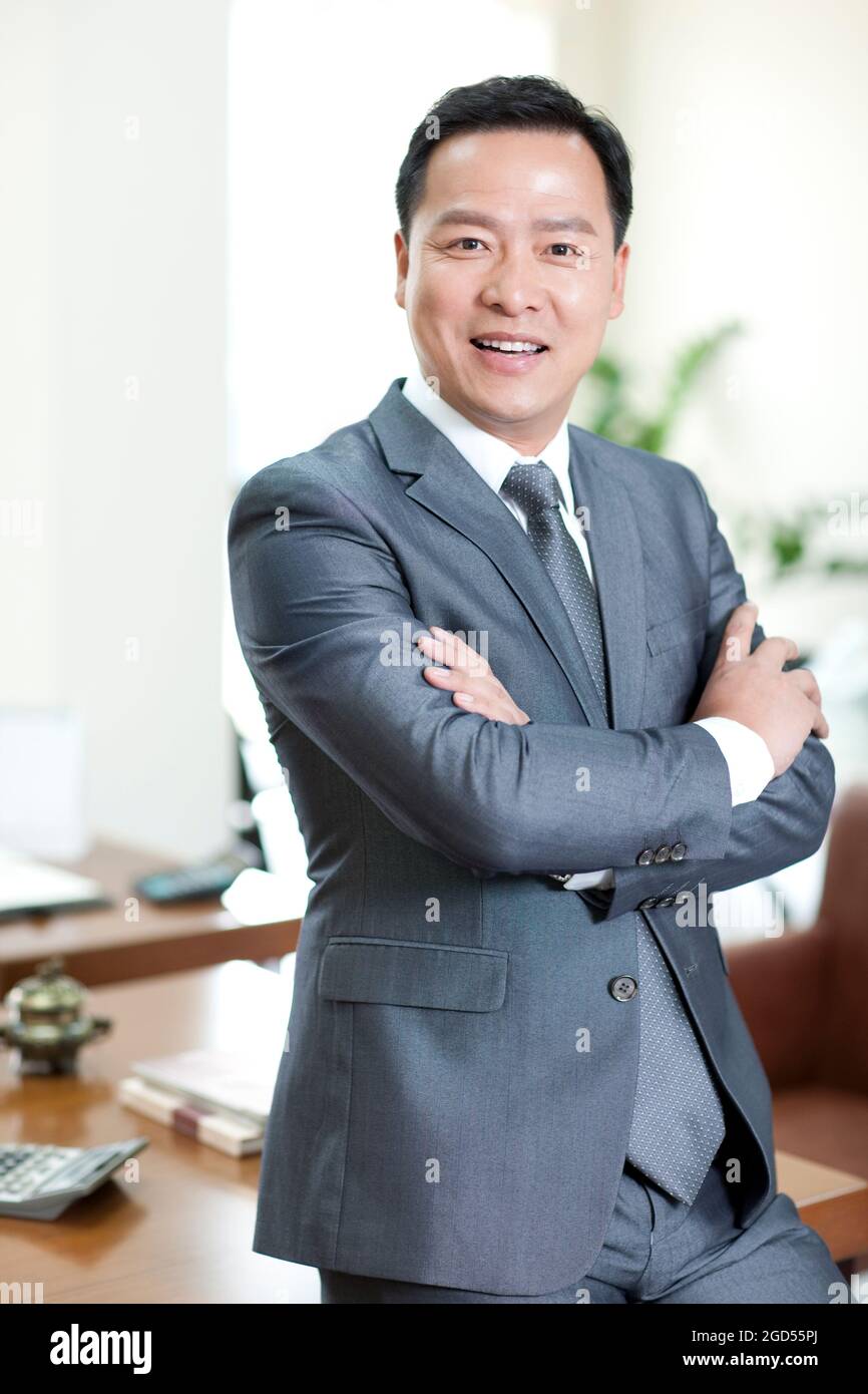 Mature businessman in office with arms crossed Stock Photo - Alamy