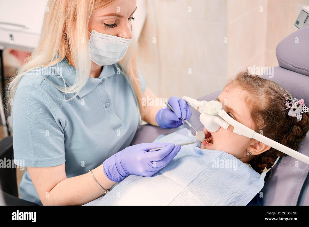 Female dentist checking child teeth with dental explorer and mirror