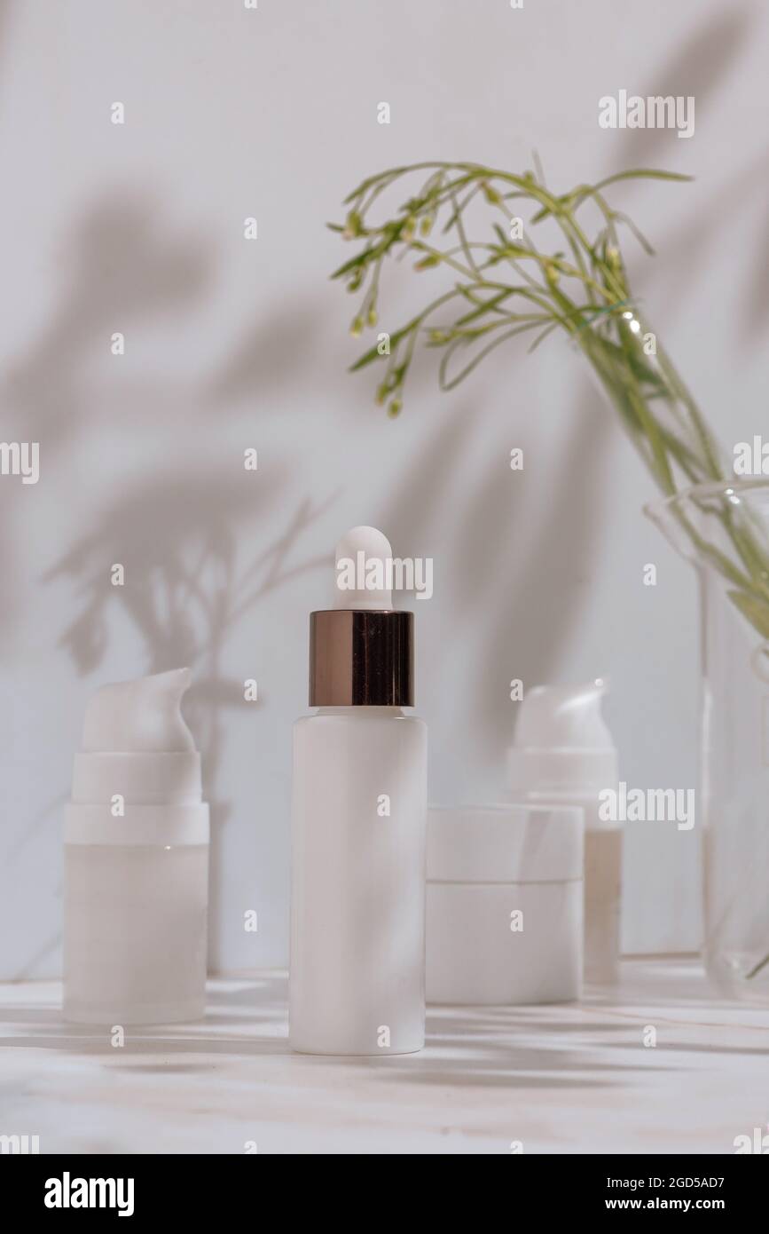 Natural cosmetic products in white packaging with laboratory glassware. Science and skincare concept Compositions with cosmetic packaging in a medical Stock Photo