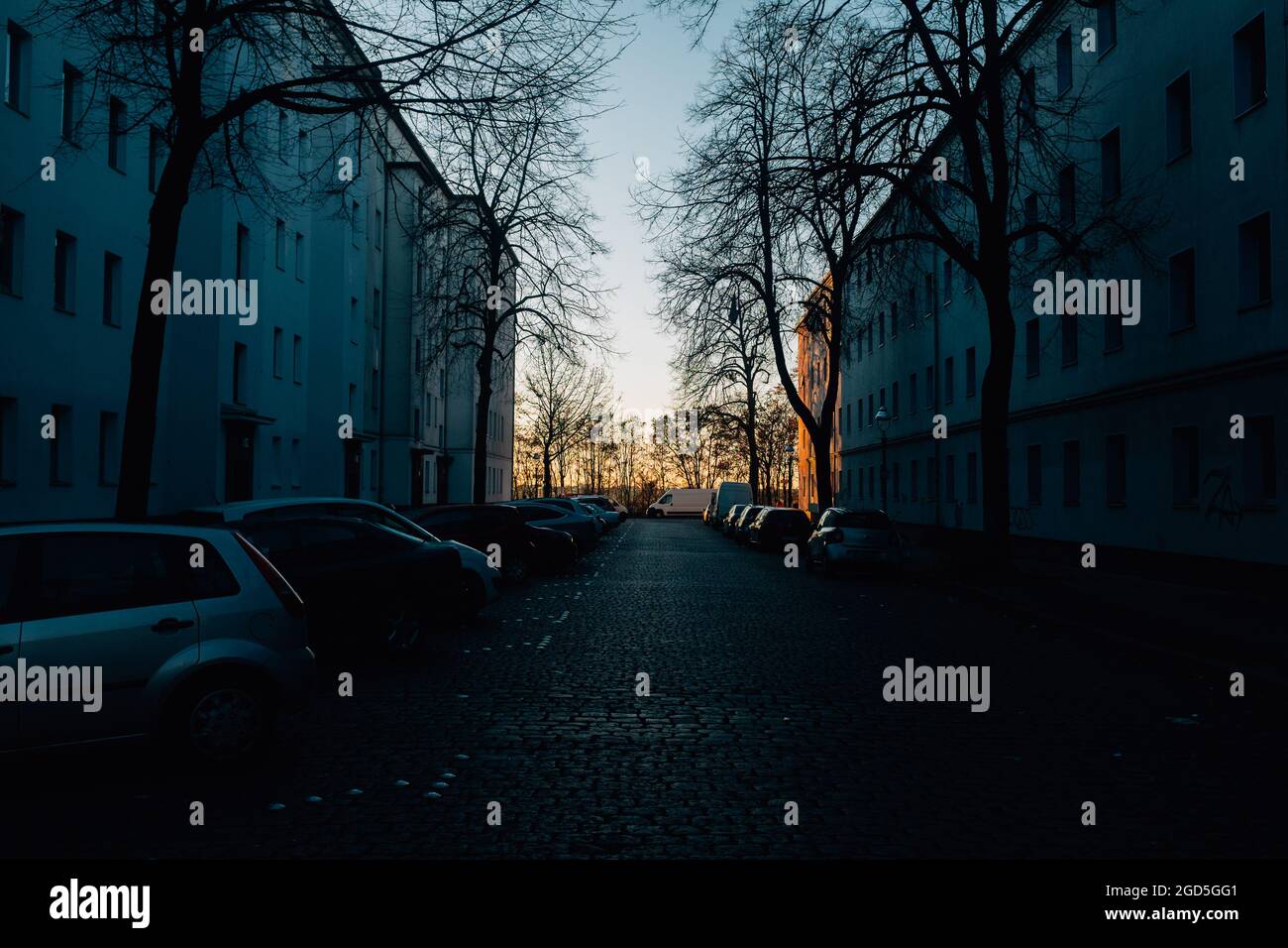 Dark road between buildings and parked cars in Berlin, Neukolln Stock Photo