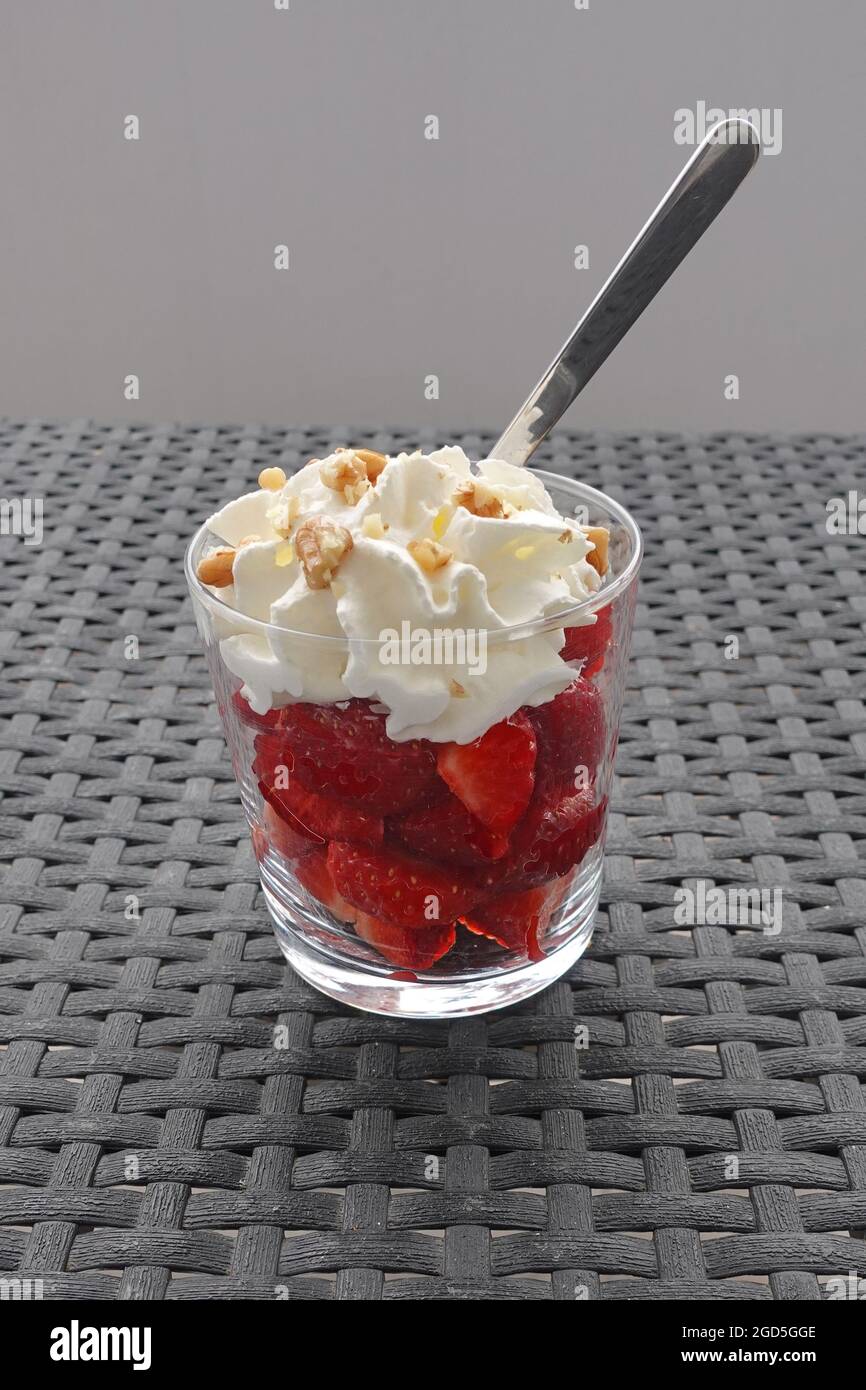 Strawberries with whipped cream and walnuts. Fruit dessert. Stock Photo