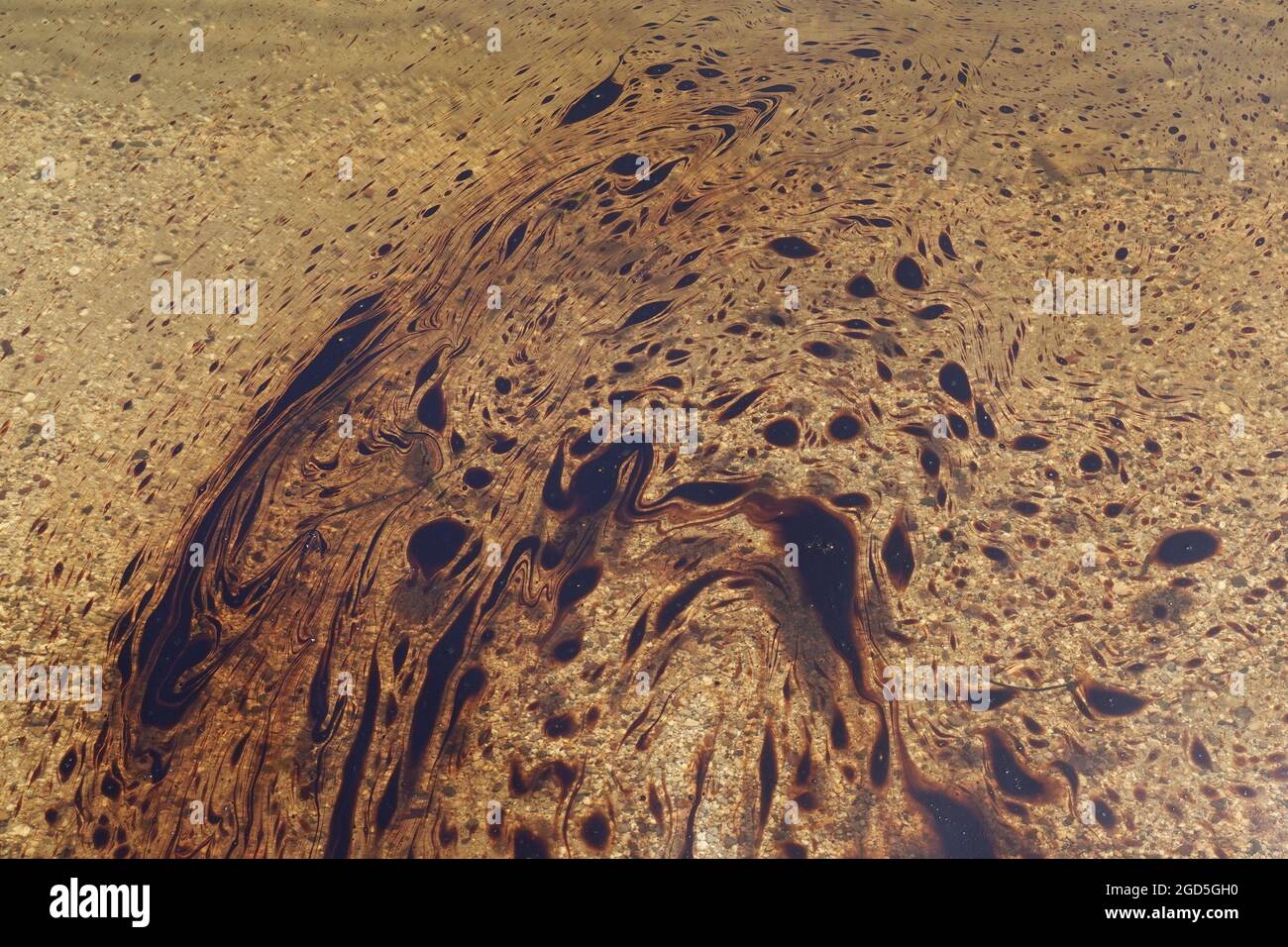 Black tar abstract fluid shapes on sea water surface. Insoluble substance background. Stock Photo