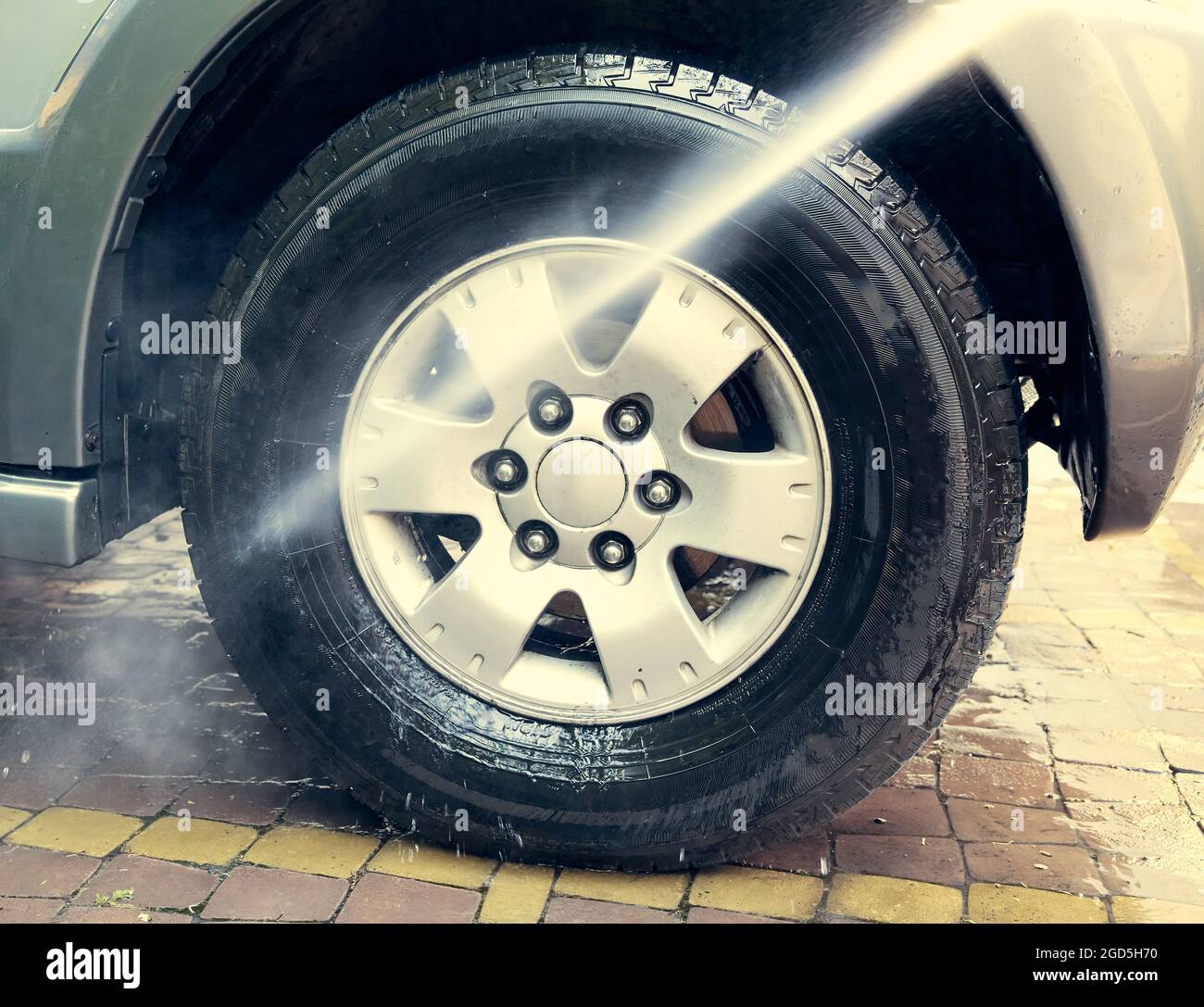 Jet washes a car wheel in the yard of  house. Odessaa Ukraine, colored, full frame, natural light. Stock Photo