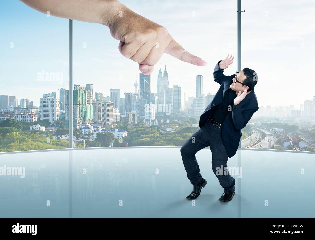 A scared businessman full-height in a scare pose and a giant hand pointing at him, on the office background. Business and management. Employment issue Stock Photo