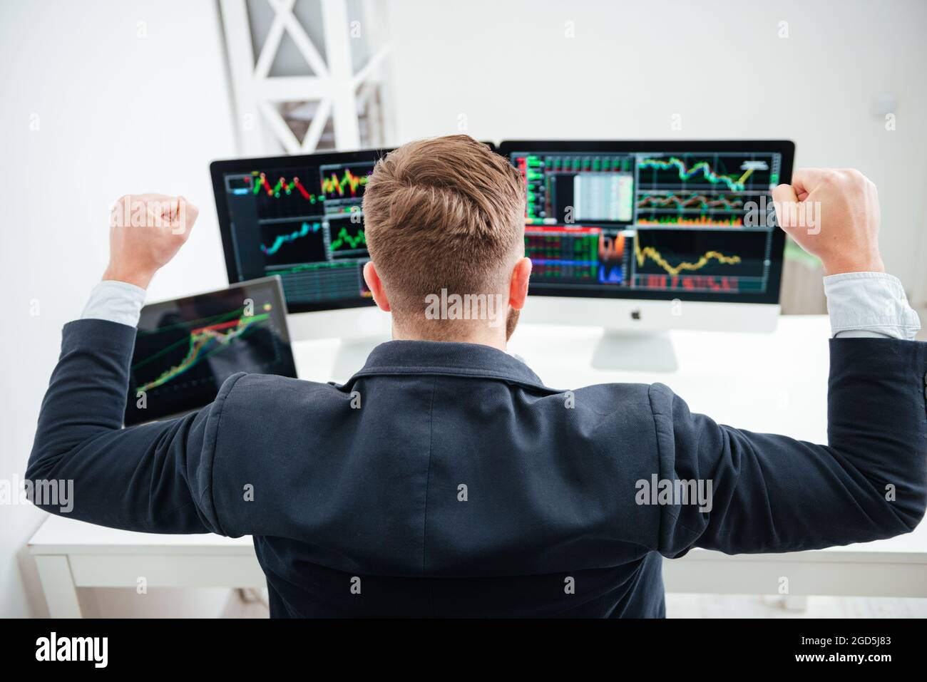 Back view of happy successful businessman sitting with raised hands and ...