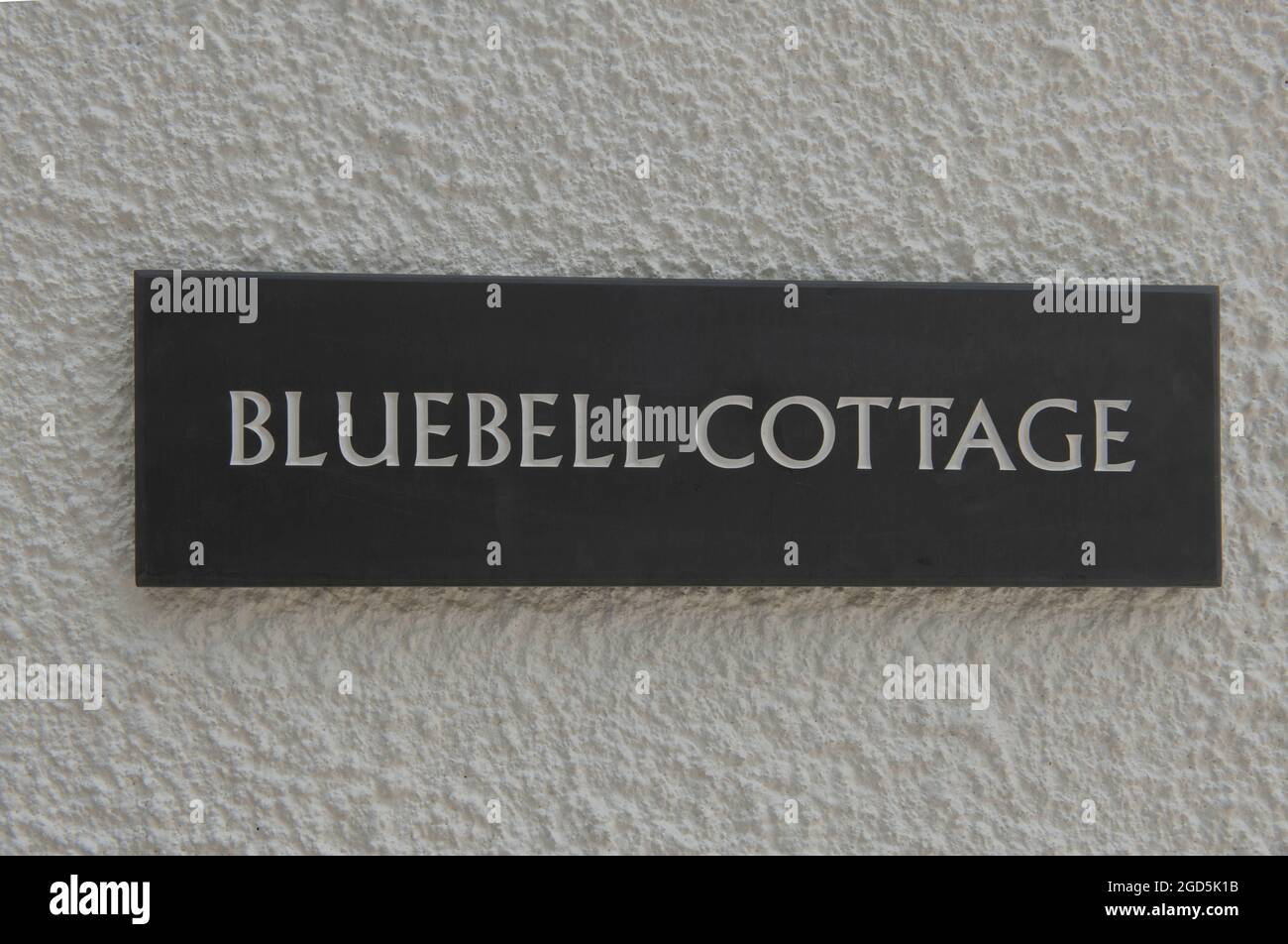 'Bluebell Cottage' Sign Engraved on a Welsh Grey Slate Tile and Attached to a White Rendered Wall in Rural Devon, England, UK Stock Photo