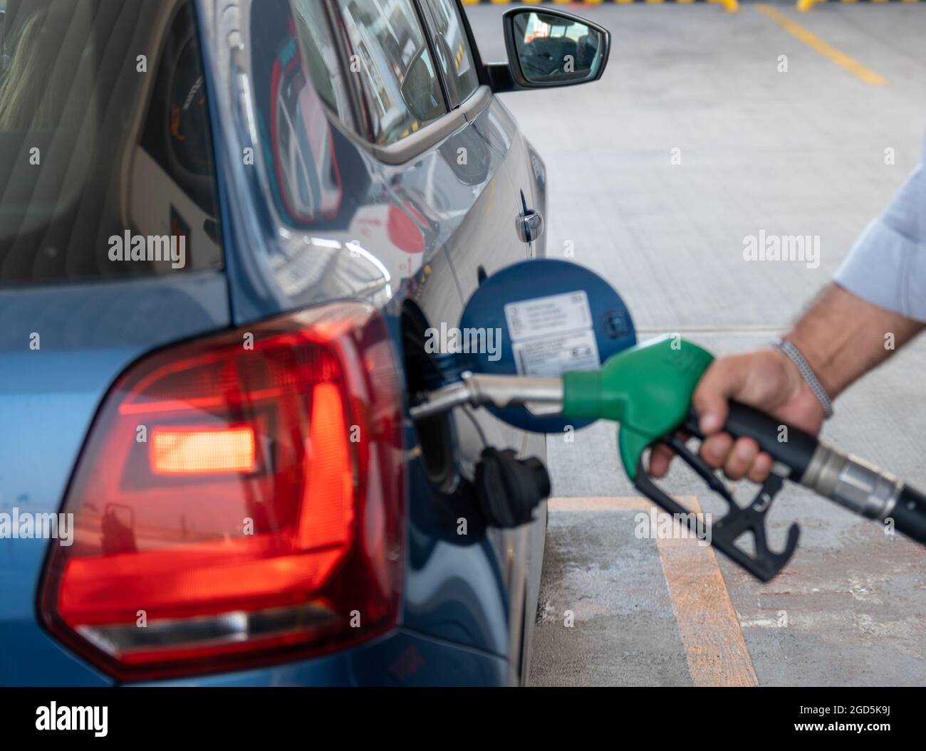 Man fueling up his blue car with his hand. Gasoline station attendant pumping oil in the supply tank Stock Photo