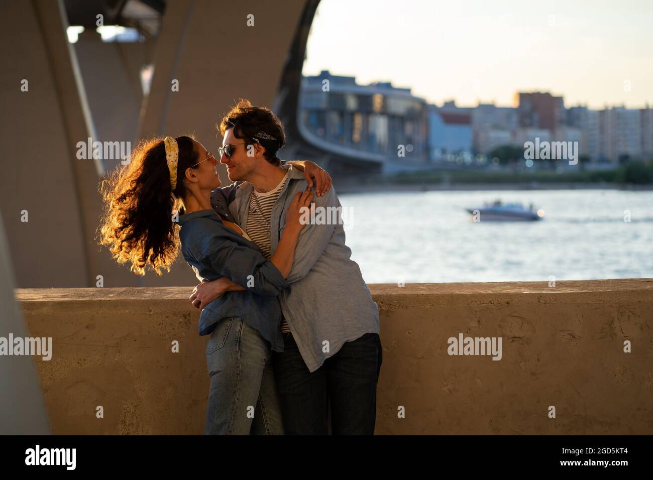 Two lovers kiss at sunset. Happy stylish couple embrace. Lovely young man and woman hug in sunlight Stock Photo