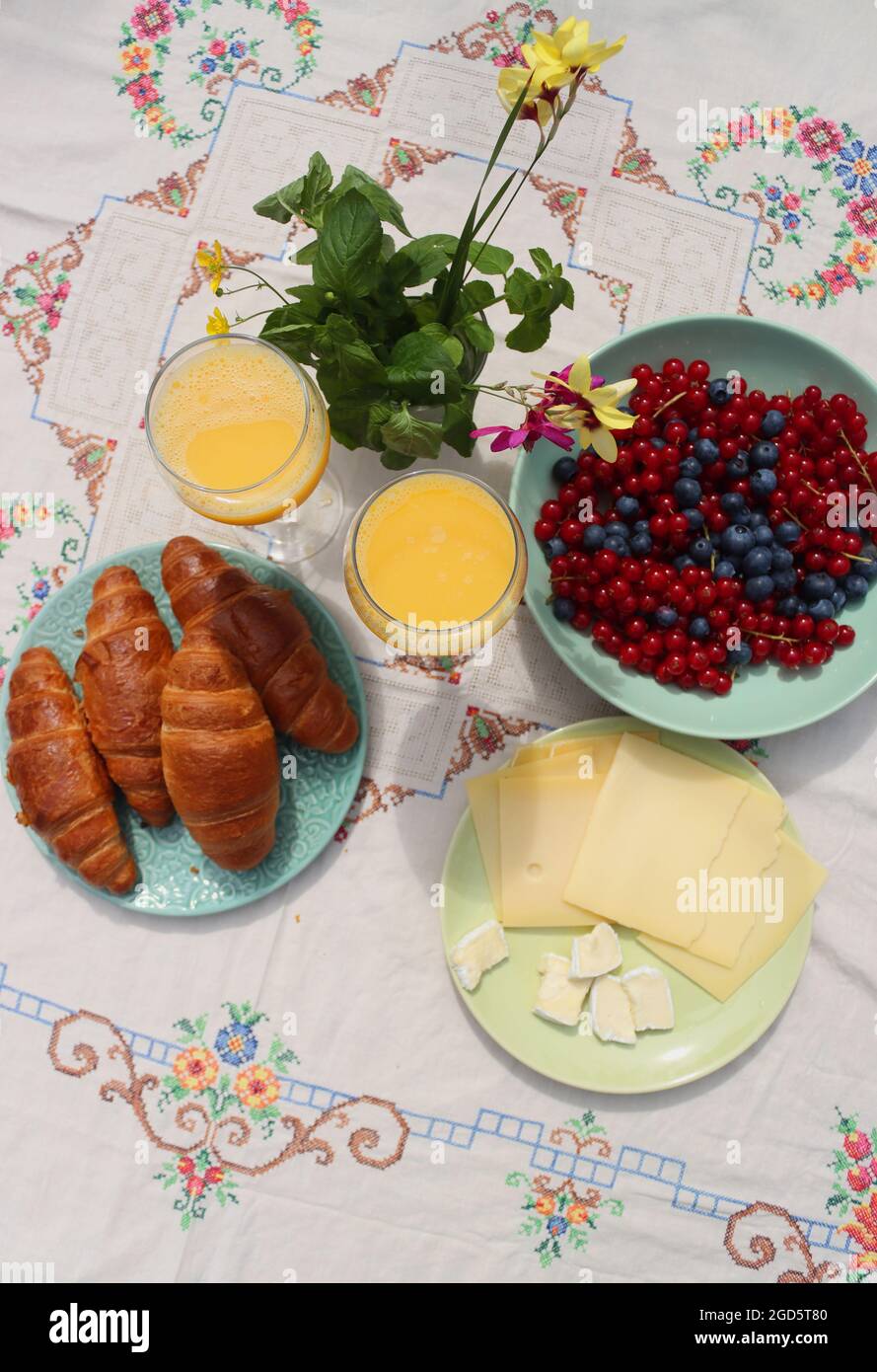 Breakfast on a table. Freshly baked croissants, cheese, red current, blue berries and two glasses of orange juice. Healthy eating concept Stock Photo