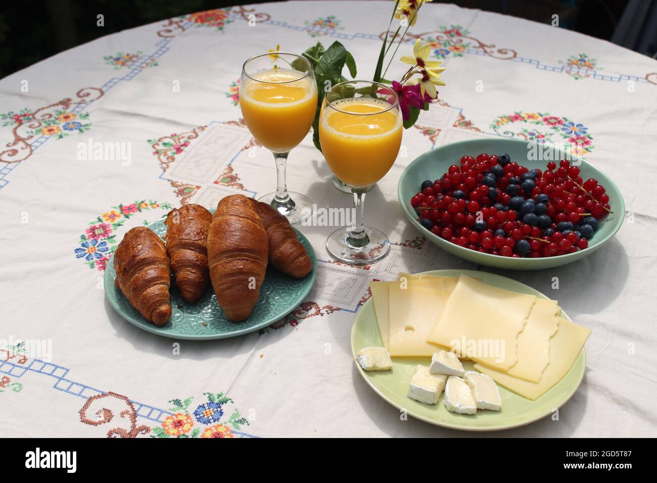 Breakfast on a table. Freshly baked croissants, cheese, red current, blue berries and two glasses of orange juice. Healthy eating concept Stock Photo