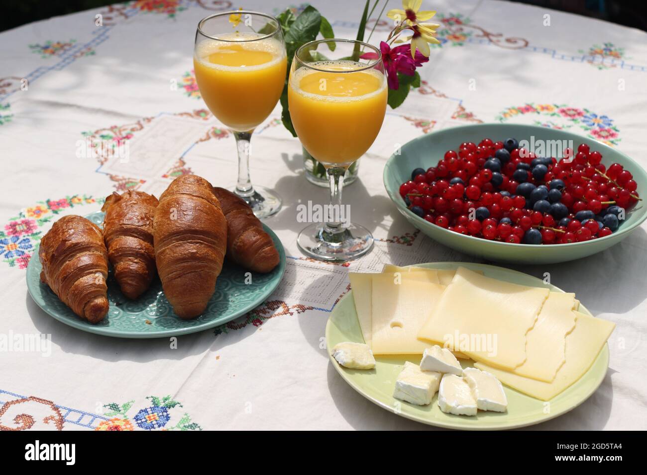 Breakfast on a table. Freshly baked croissants, cheese, red current, blue berries and two glasses of orange juice. Healthy eating concept Stock Photo