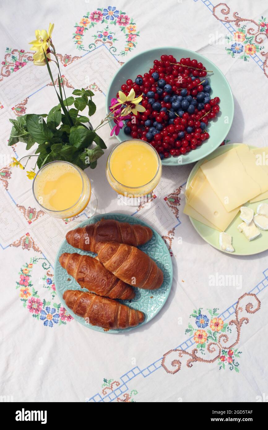 Breakfast on a table. Freshly baked croissants, cheese, red current, blue berries and two glasses of orange juice. Healthy eating concept Stock Photo