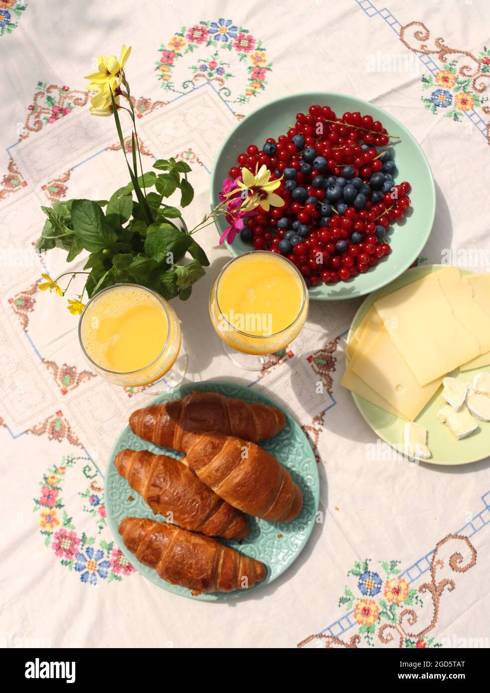 Breakfast on a table. Freshly baked croissants, cheese, red current, blue berries and two glasses of orange juice. Healthy eating concept Stock Photo