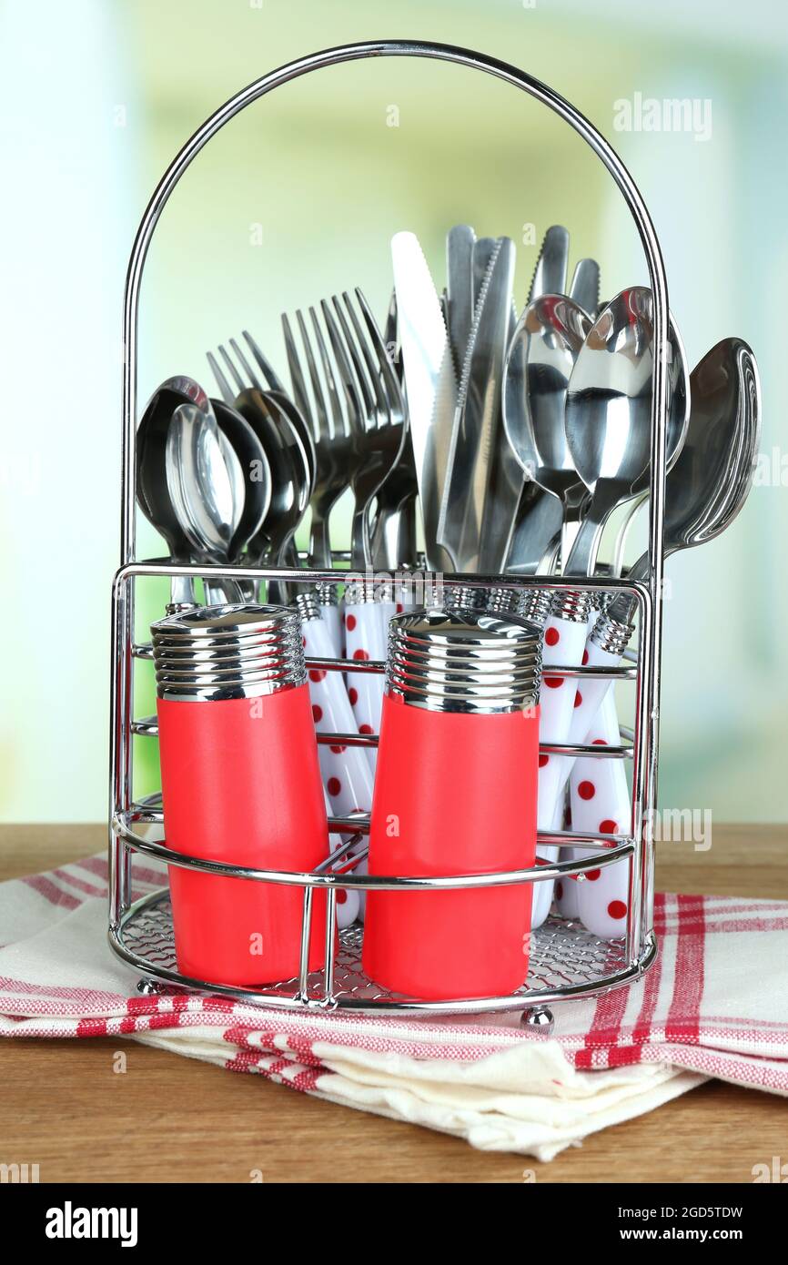 Kitchen cutlery in metal stand on wooden table on bright background Stock  Photo - Alamy