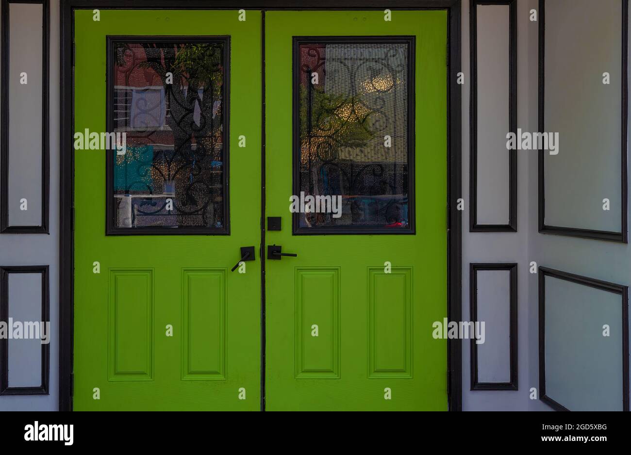 Lime green doors and white exterior wall with black trim draw the eye to the entrance to this building Stock Photo