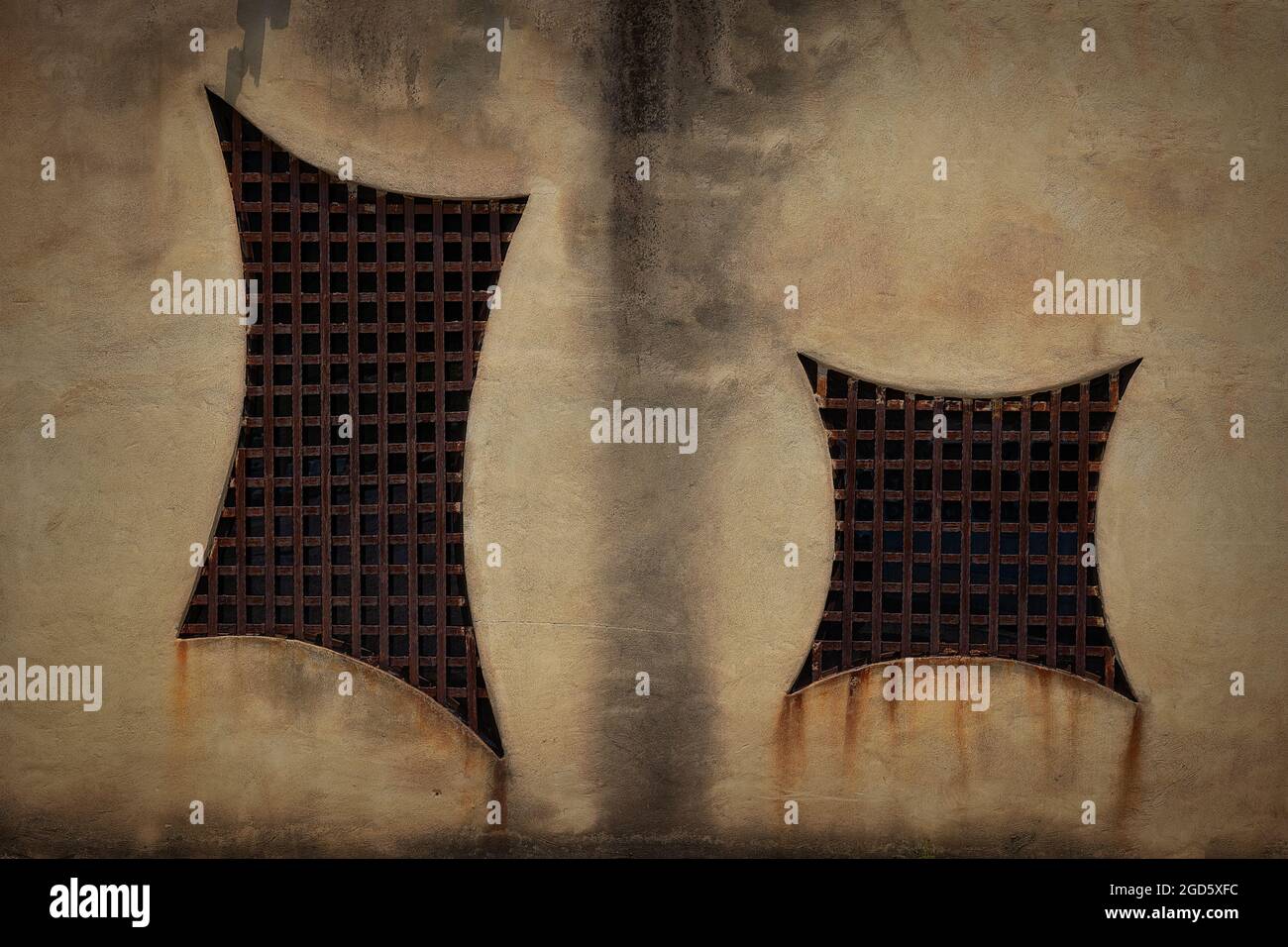 Rusty steel grates windows with rust stains dripping down the side of a