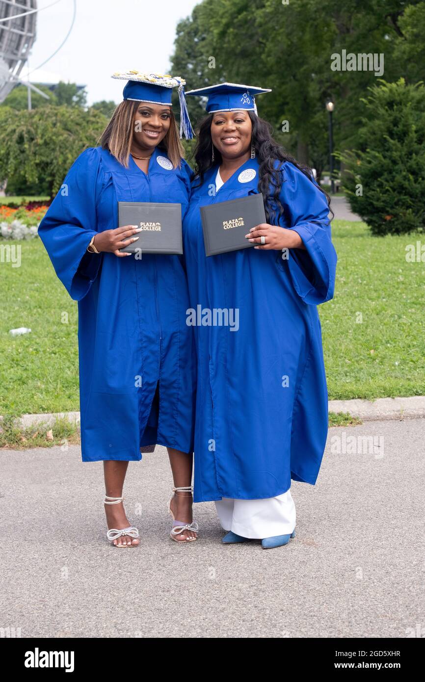 2 beautiful Plaza College graduates in cap and gown pose for a photo with their diplomas. Near the Unisphere in Flushing Meadows Corona Park. Stock Photo