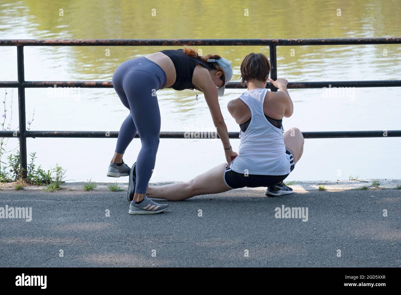 A very fit personal trainer takes a client through groin stretching
