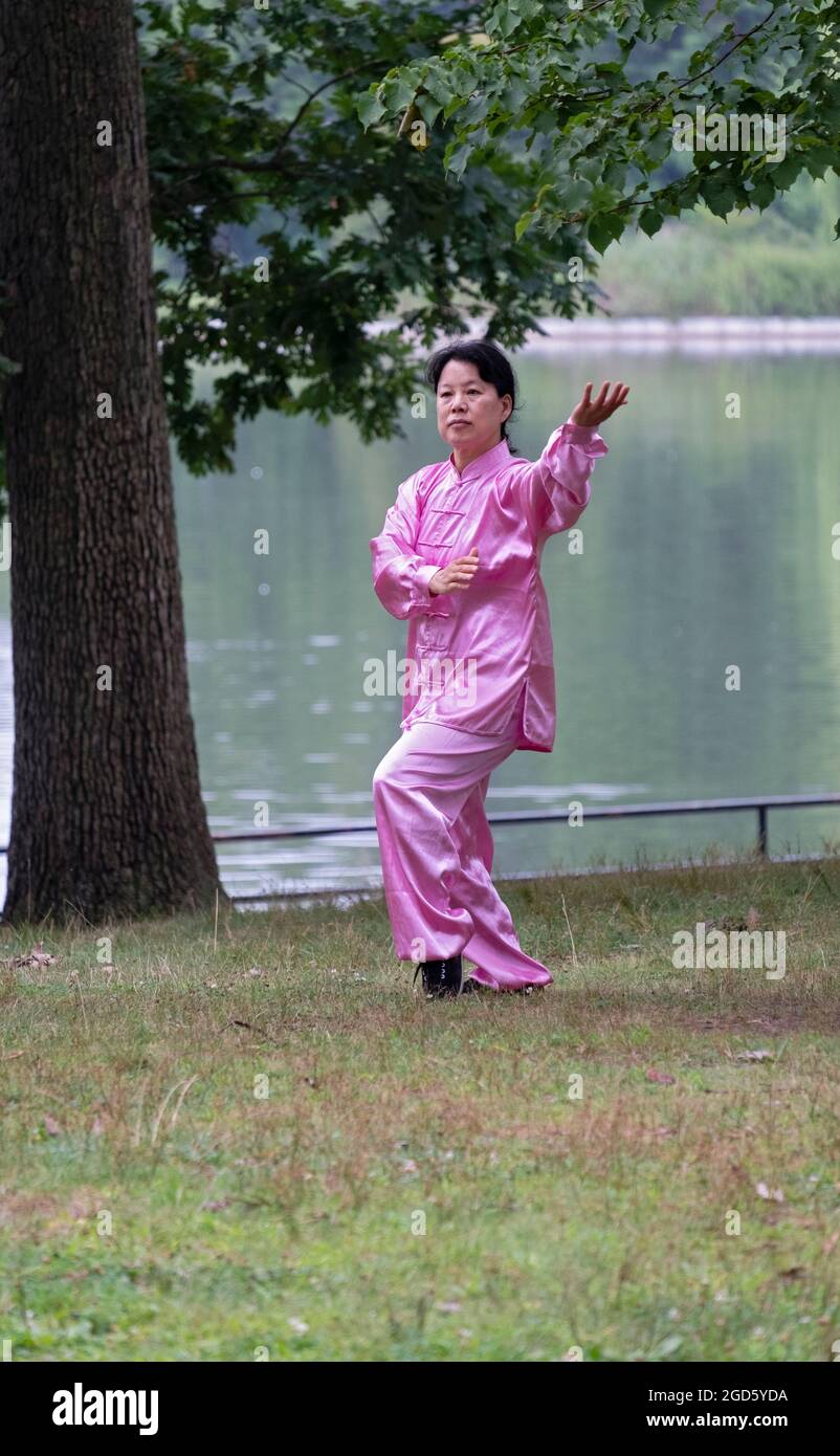 An attractive woman in a shiny pink Tai Chi suit goes through graceful