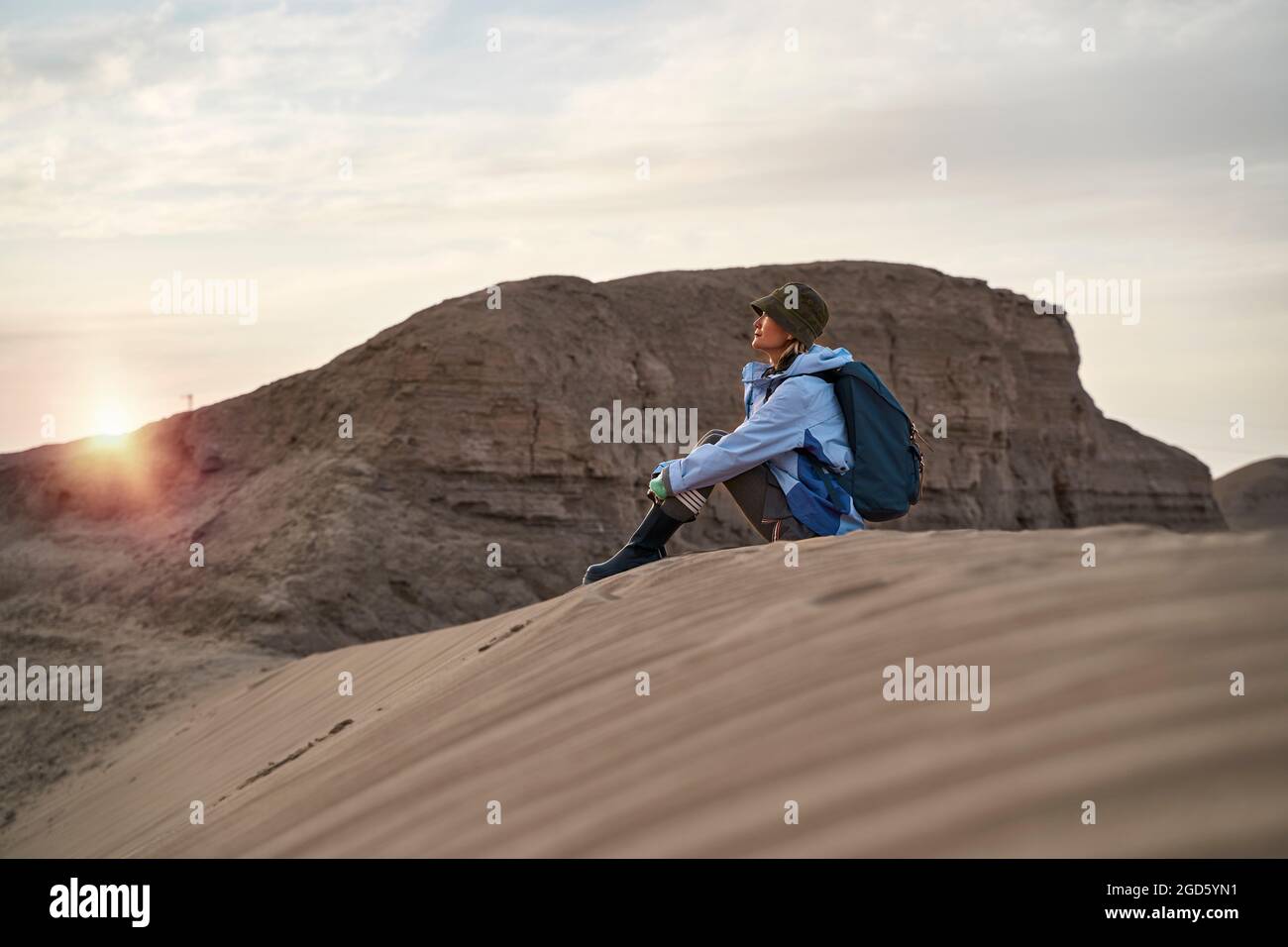 young asian woman backpacker sitting on ground relaxing resting watching sunset Stock Photo