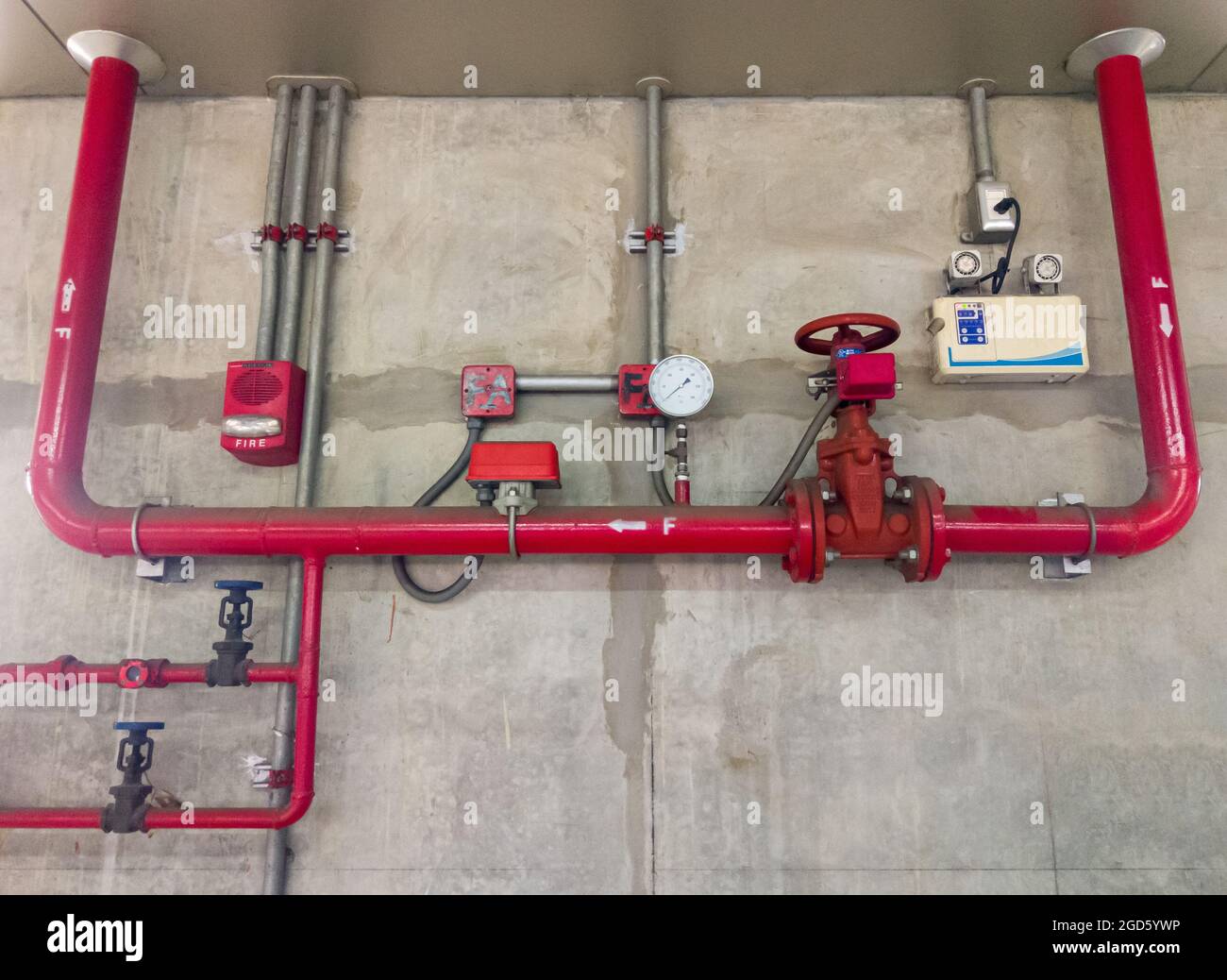 The red metal pipe and large valve of the fire fighting system near the