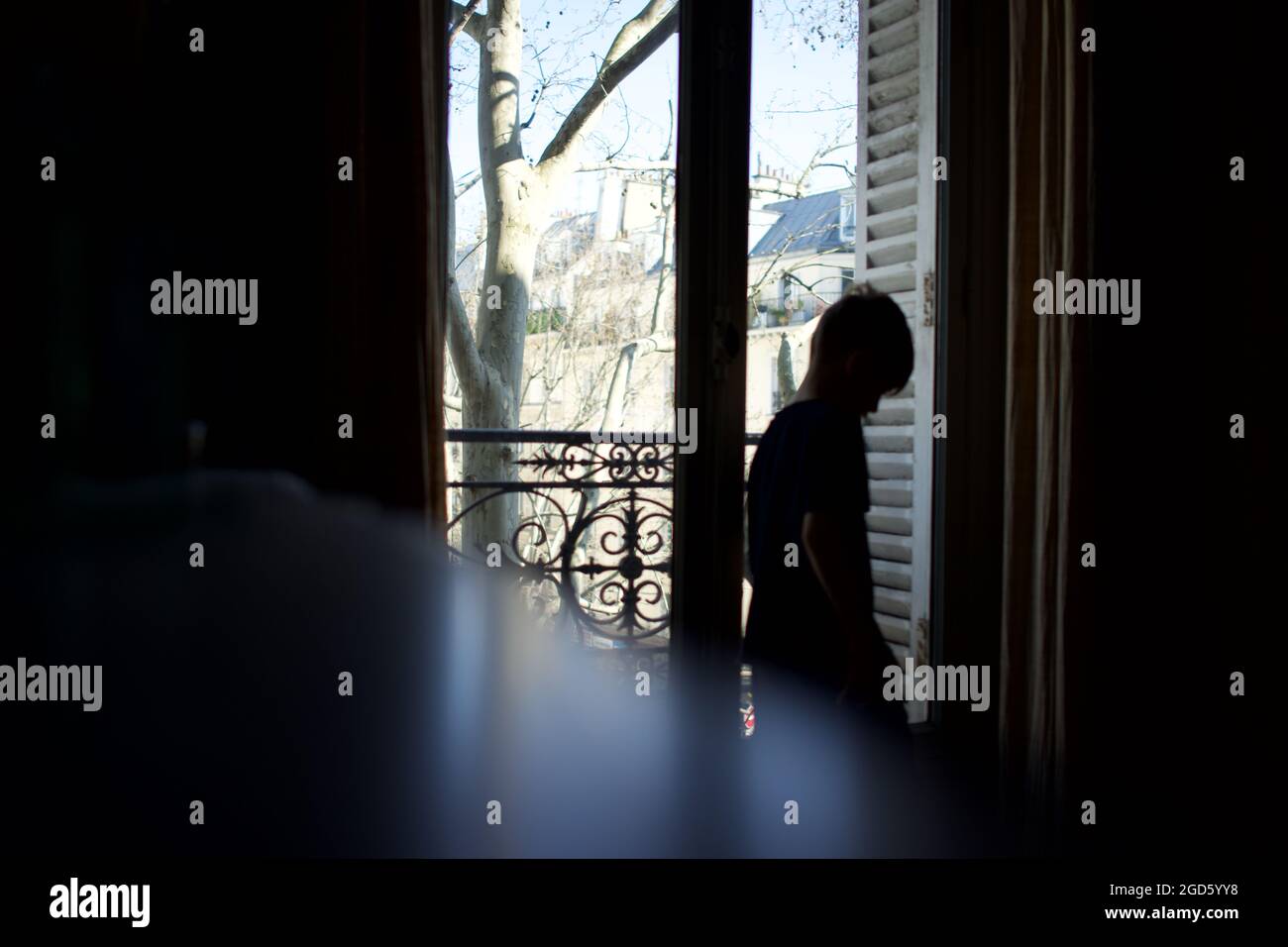 Vulnerable, sad, depressed young child, silhouetted by window - townhouse interior Stock Photo