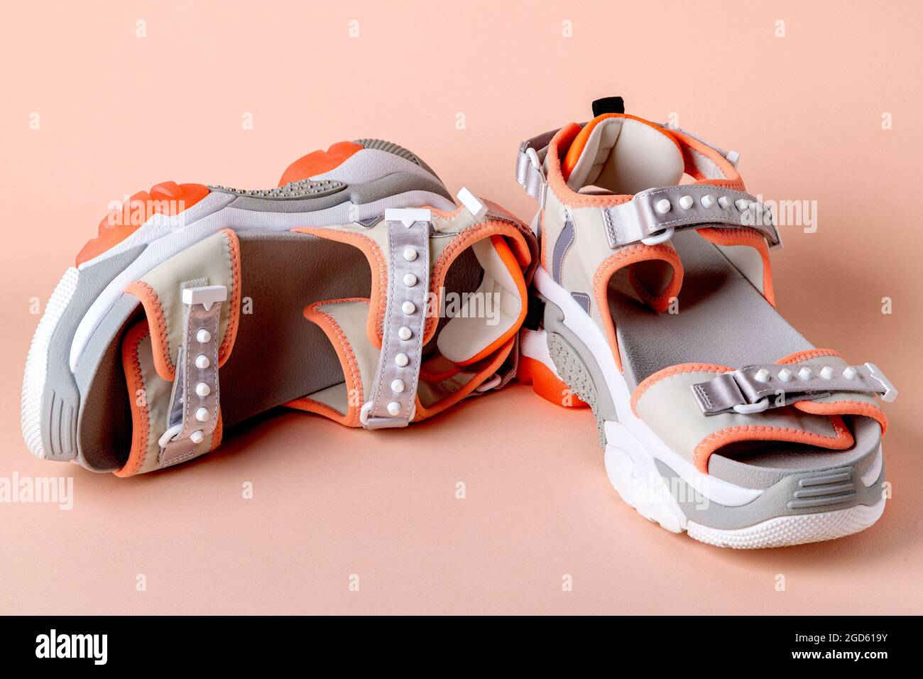 Women's, fashionable, sports sandals with orange accents on a pink background. New youth shoes for girls. Front view. Stock Photo