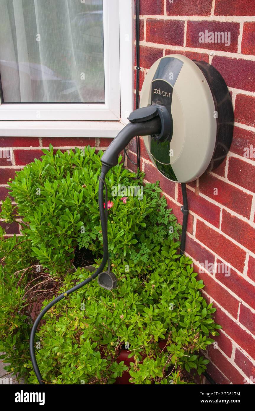 Charging an electric powered car on the driveway of a suberban semi-detached house in the United Kingdom Stock Photo