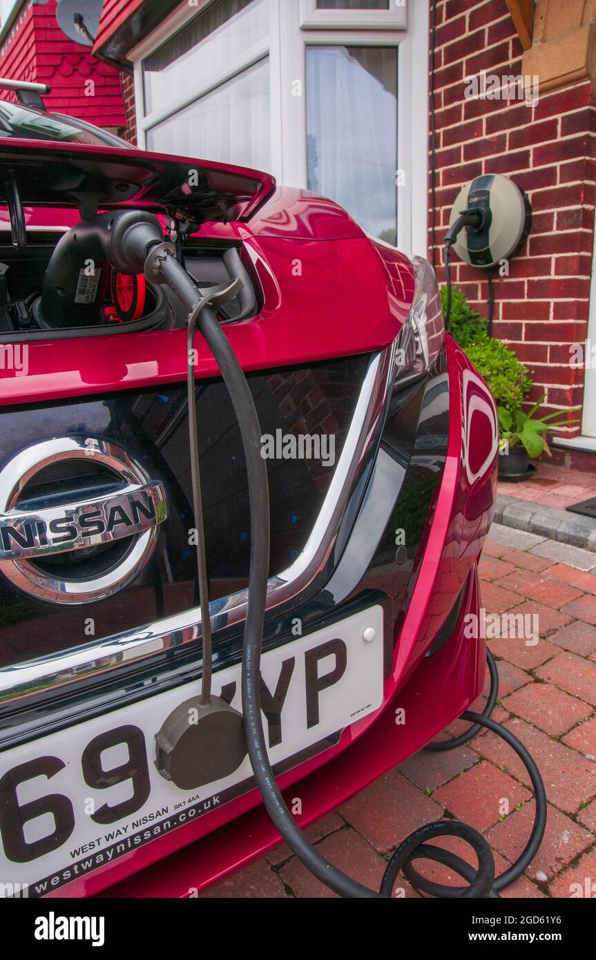 Charging an electric powered car on the driveway of a suberban semi-detached house in the United Kingdom Stock Photo
