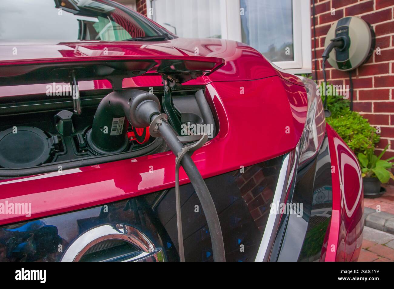 Charging an electric powered car on the driveway of a suberban semi-detached house in the United Kingdom Stock Photo