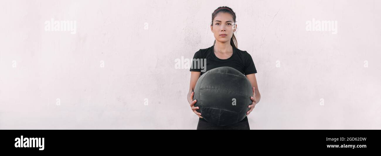 Woman athlete cross training carrying throwing heavy medicine ball doing squats and ball slam