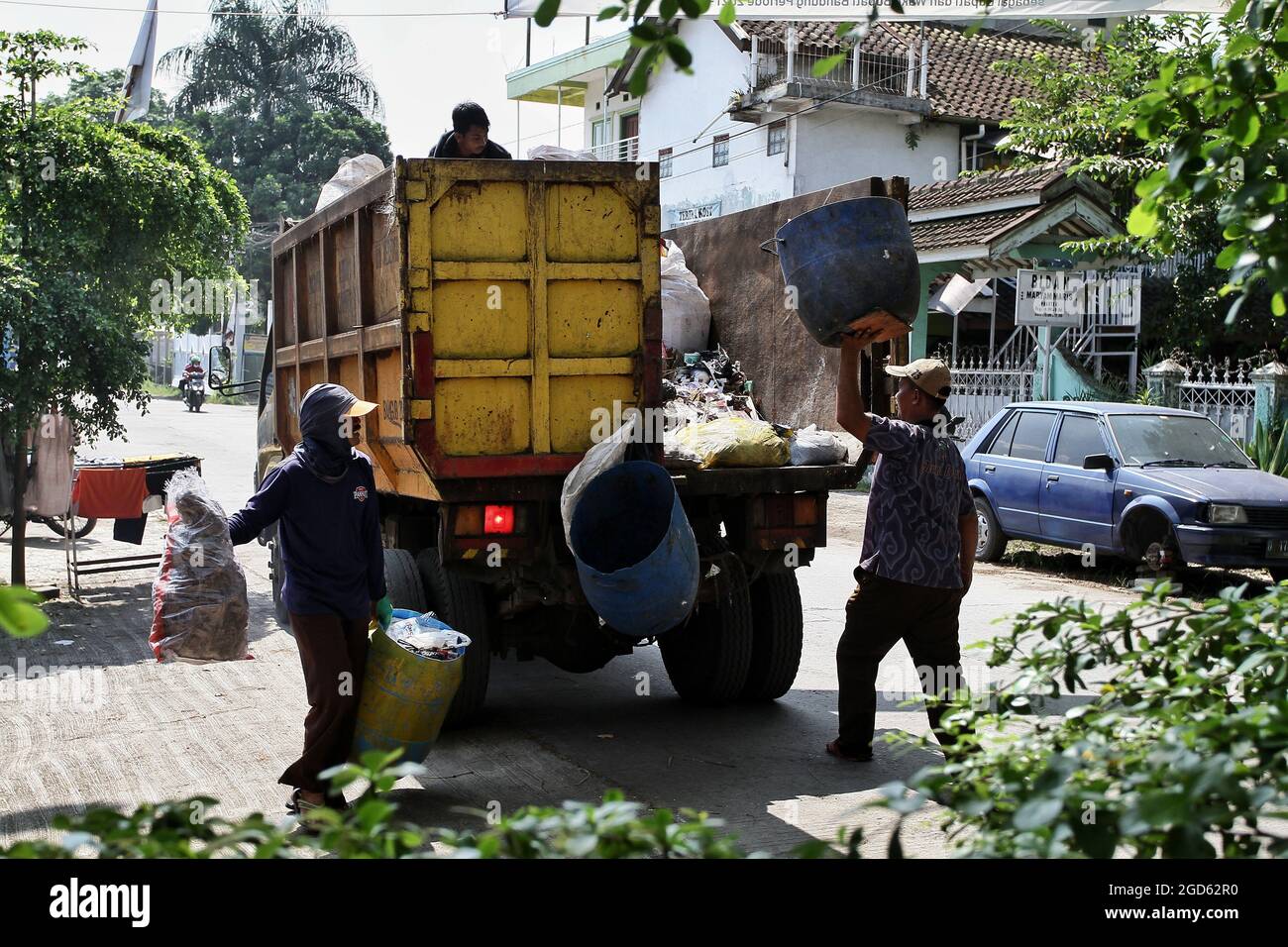 Bandung, West Java, Indonesia. 2 men are carrying garbage to the garbage truck Stock Photo
