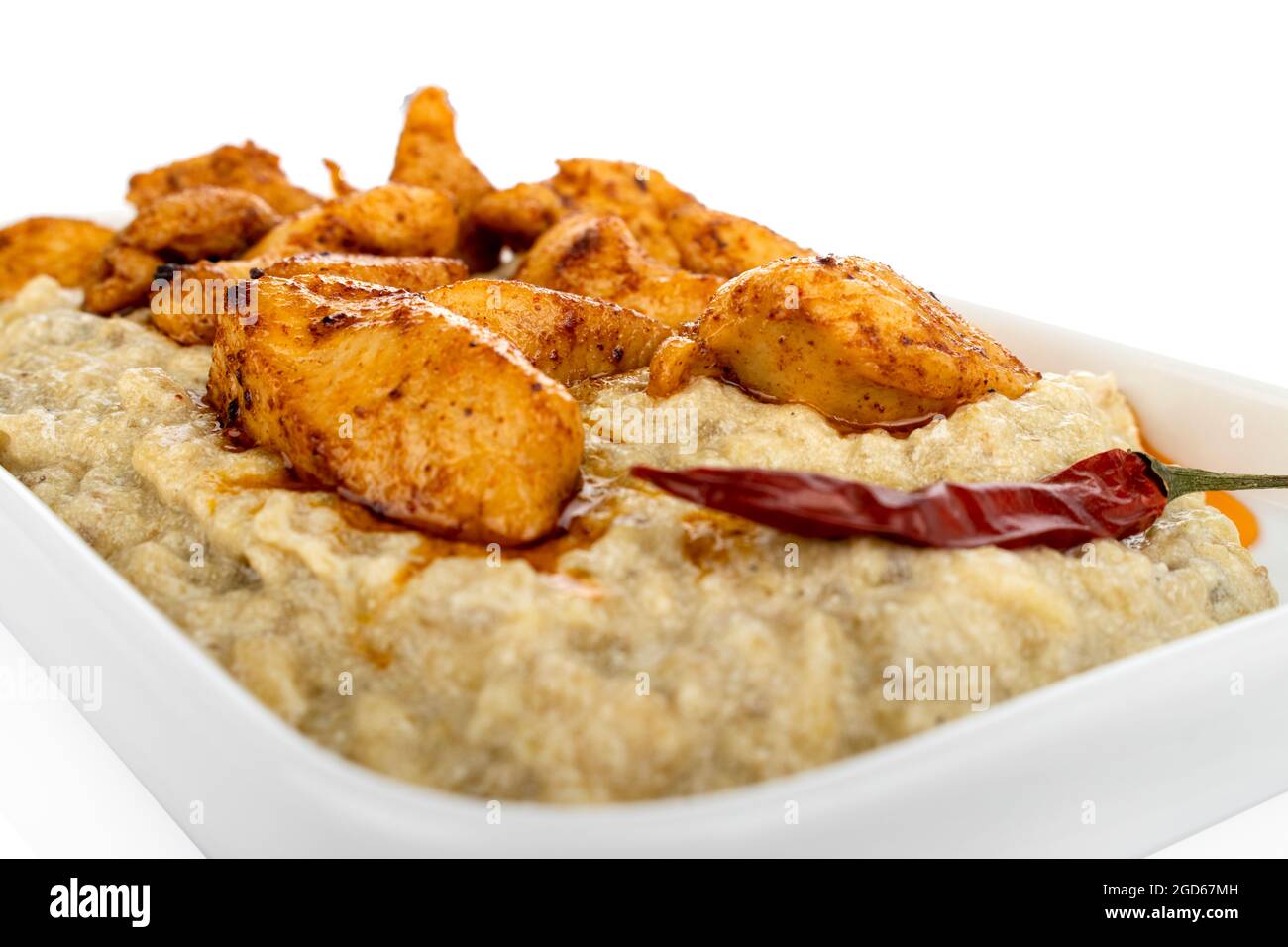 Chicken with aubergine puree, on white plate, on white background, eggplant pure, roasted eggplant Stock Photo