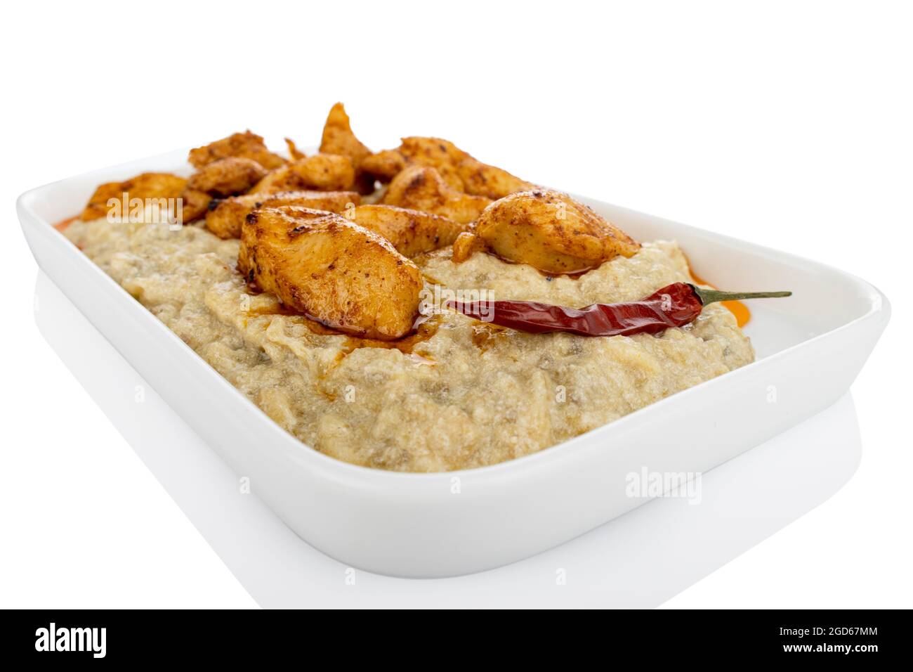 Chicken with aubergine puree, on white plate, on white background, eggplant pure, roasted eggplant Stock Photo