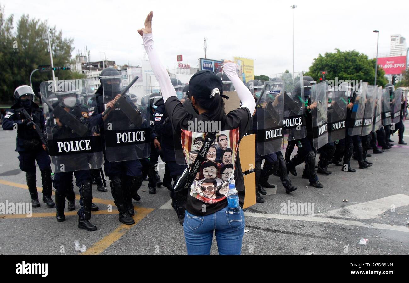 A protester raises her three finger salute in front of riot policemen ...