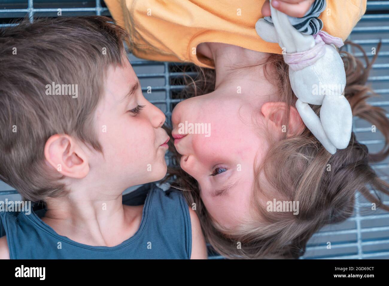 portrait of twins boys and girls are kissing lying on a metal grate Stock Photo