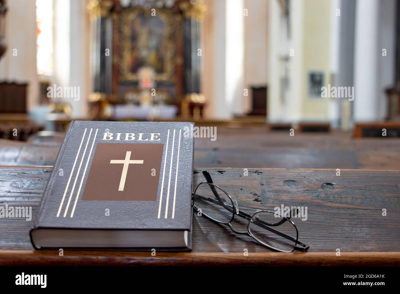The Bible on the table of a prayer bench in the church with a altar. Stock Photo