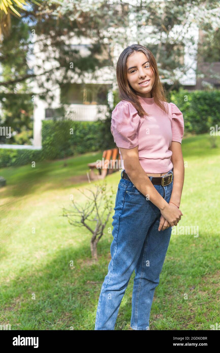 Vertical portrait of a Latina teenage girl smiling and looking at camera outdoors Stock Photo