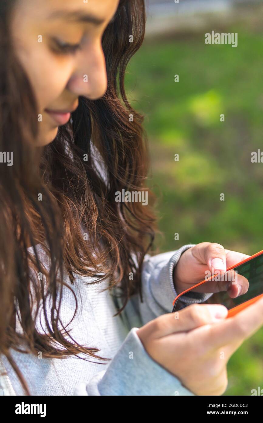closeup of the hands of a brunette teenage girl using a cell phone ...