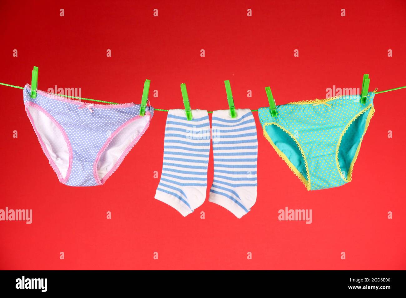 Baby clothes hanging on clothesline, on color background Stock Photo