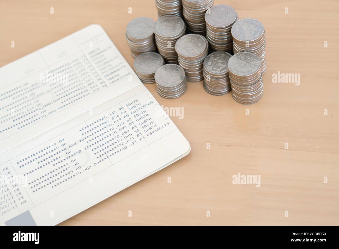 Close up of unstable stack of silver coins on bank passbook. Stock Photo